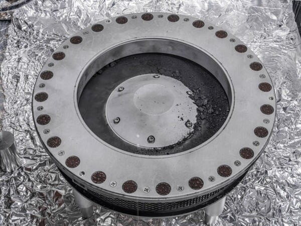 소행성 탐사선 '오시리스-렉스' 샘플 수집기 외부 모습. 가운데 오른쪽에 흩어진 먼지들이 베누에서 채취한 샘플. [미 항공우주국(NASA)]